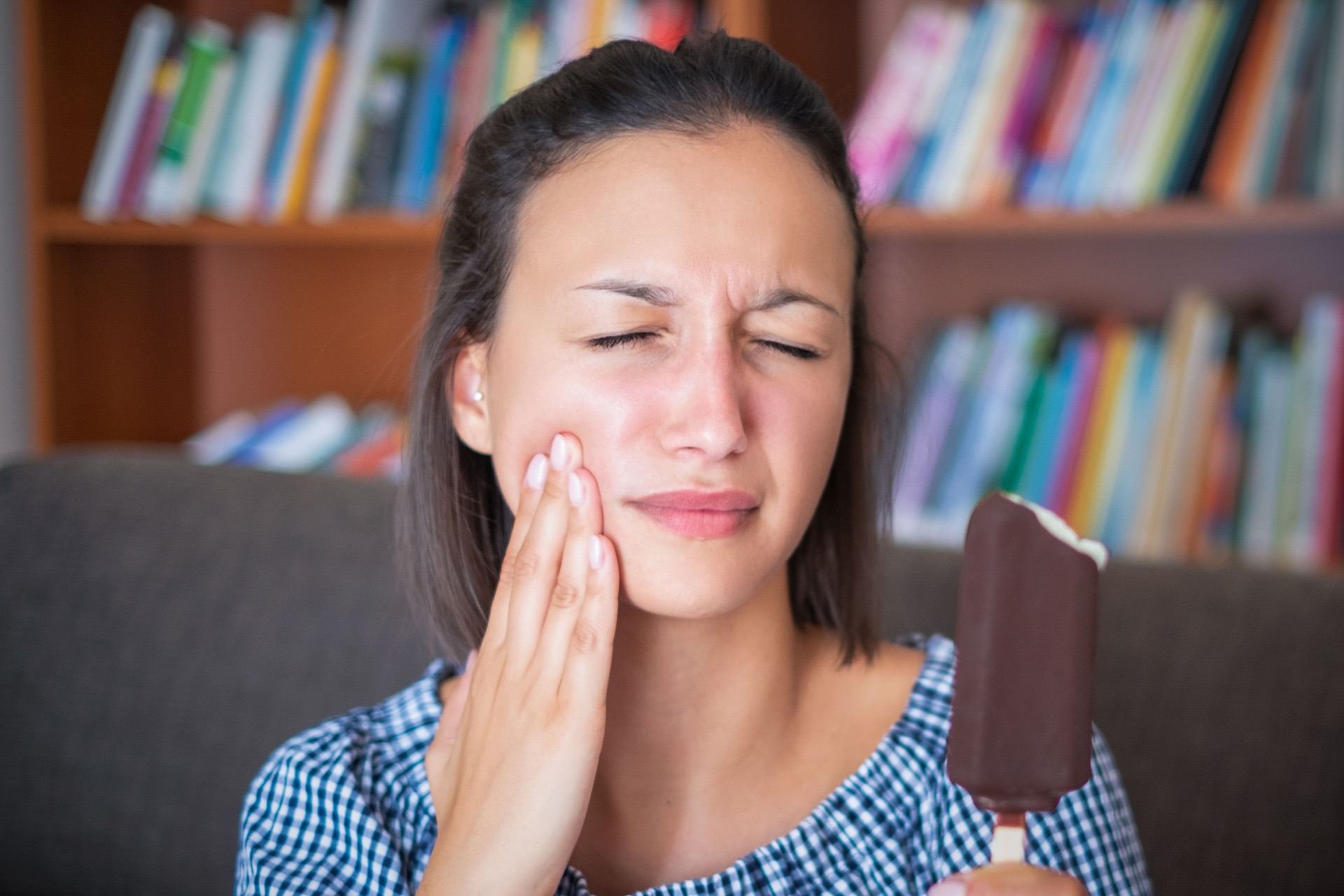 Young woman experiencing sudden tooth sensitivity after eating ice cream