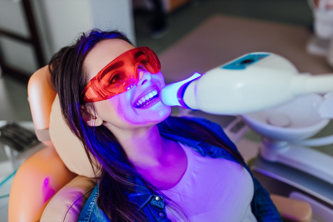 Woman having her teeth whitened at dentist office